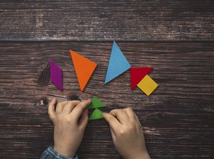 Kinder lernen mit Formen. Foto: Adobe Stock/Natasha Lebedinskaya Ein Kind legt Tangram-Elemente